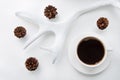 Christmas and winter concept. White mug of hot black coffee and cones, horns on white background. Top view. Royalty Free Stock Photo