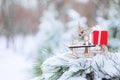 Christmas winter holiday greeting card. Wooden cute reindeer on sled, red gift boxes on white snow and green christmas trees outd