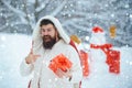 Christmas man in snow. Christmas winter people portrait. Man with red gift playing with snowman in winter park. Handsome