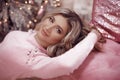 Christmas Winter portrait of attractive woman with makeup and long wavy hairstyle. Beutiful blond girl wears in pink dress over