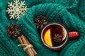 Christmas and winter traditional hot beverage. Mulled wine in red mug with spice wrapped in warm green sweater.