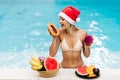 Christmas woman beautiful smiling in Santa`s hat with a tropical fruits Royalty Free Stock Photo