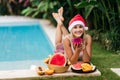 Christmas woman beautiful smiling in Santa`s hat with a tropical fruits Royalty Free Stock Photo