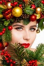 Christmas Woman Face Make up. Beautiful Girl Portrait in Fir tree Wreath. Red Lipstick and Eyes Makeup. Winter Skin Care