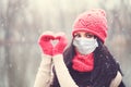 Christmas Woman in medical protective face mask making heart, winter portrait
