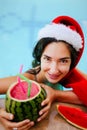 Christmas woman in Santa& x27;s hat with watermelon cocktail in swimming pool Royalty Free Stock Photo