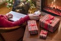 Christmas. Woman using laptop for searching gift ideas sitting at table with ready gift boxes and cup of cocoa and marshmallows Royalty Free Stock Photo