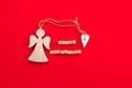 Christmas wooden angel with heart and twine with words Merry Christmas on little bricks on bright red background. Royalty Free Stock Photo