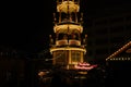 Christmas wooden pyramid rotates with nativity scene at night, people buy sweets, fast food, mulled wine during Christmas market, Royalty Free Stock Photo