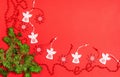 Christmas wooden toys in the form of a white angel and a red snowflake with bright red beads, a fir branch on a red background Royalty Free Stock Photo