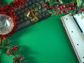 Flat lay of Christmas decorations, a keyboard, notebook, and pen on a vibrant green Royalty Free Stock Photo