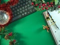Christmas Workspace with Decorations - Flat lay of Christmas decorations, a keyboard, notebook, and pen on a vibrant green Royalty Free Stock Photo