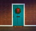 Christmas wreath on blue front door with welcome mat.