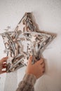 Christmas wreath.childrens hands hang a white wreath in the shape of a star on a white wall. girl in a sweater holds a