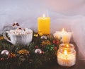 Christmas wreath, cup of marshmallows and lighted candles. Festive Christmas composition.