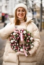 Christmas wreath decorated with pink and white balls, pink ribbon and flowers is held by a pretty woman Royalty Free Stock Photo