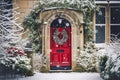 Christmas wreath and decoration on a classic red door on snowing winter holiday, Merry Christmas and Happy Holidays wishes, Royalty Free Stock Photo