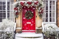 Christmas wreath and decoration on a classic red door on snowing winter holiday, Merry Christmas and Happy Holidays wishes, Royalty Free Stock Photo