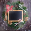 Christmas wreath with decorations and blank chalkboard with wooden frame on  wooden background.  New Year decoration. Top view, Royalty Free Stock Photo