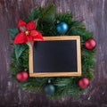 Christmas wreath with decorations and blank chalkboard with wooden frame on  wooden background.  New Year decoration. Top view, Royalty Free Stock Photo