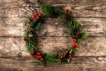 Christmas wreath of Fir branches, cones, red decoration on wooden background with snowflakes. Royalty Free Stock Photo