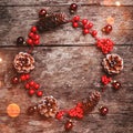 Christmas wreath of Fir branches, cones, red decorations on dark wooden background. Royalty Free Stock Photo