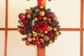 Christmas wreath of fir branches and gold and red balls and red bells. Royalty Free Stock Photo