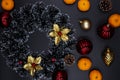 Christmas wreath, fir tree decor and tangerines on black background. Winter Holiday season composition Royalty Free Stock Photo