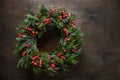 Christmas wreath of fresh natural spruce branch with red berries on brown background. New Year. Xmas holiday. Royalty Free Stock Photo