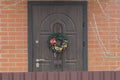 Christmas wreath hanging on a brown door on a red brick wall Royalty Free Stock Photo