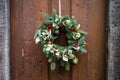 A Christmas wreath hanging on a rope on an old wooden front door Royalty Free Stock Photo