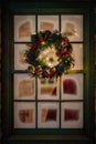 christmas wreath with lights on outside of window in night time
