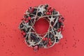 Christmas Wreath Made of branches decorated with gold wooden stars and red berry bubbles isolated on red background. Creative diy Royalty Free Stock Photo