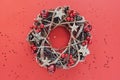 Christmas Wreath Made of branches decorated with gold wooden stars and red berry bubbles isolated on red background. Creative diy Royalty Free Stock Photo