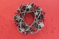 Christmas Wreath Made of branches decorated with gold wooden stars and red berry bubbles isolated on red background. Creative diy Royalty Free Stock Photo