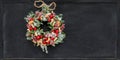 Christmas wreath made of fir branches, dried apples, cinnamon, red berries, bottle caps, red balls hanging on a black Royalty Free Stock Photo
