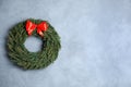 Christmas wreath made of fir branches with red bow on color wall. Space for text Royalty Free Stock Photo