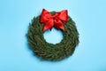 Christmas wreath made of fir branches with red bow on light blue background, top view Royalty Free Stock Photo