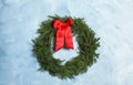 Christmas wreath made of fir branches with red bow on light blue wall Royalty Free Stock Photo