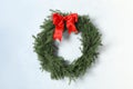 Christmas wreath made of fir branches with red bow on light wall Royalty Free Stock Photo