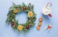 Christmas wreath made of fir branches, with small red and gold balls, slices of dried orange, shiny beads on a blue Royalty Free Stock Photo