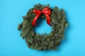 Christmas wreath made of fir tree branches with red ribbon on light blue background Royalty Free Stock Photo