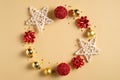 Christmas wreath made of golden and red balls decorations, stars, confetti on yellow background. Flat lay, top view. Season Royalty Free Stock Photo