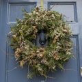 Christmas wreath made of pine and juniper, decorated with dry poppy heads, herbs, berries in green and brown tones on the front Royalty Free Stock Photo