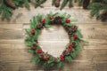 Christmas wreath made of spruce branches with holly berries on wooden board. Flat lay. Top view. Royalty Free Stock Photo