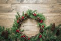 Christmas wreath made of spruce branches with holly berries on wooden board. Flat lay. Top view. Royalty Free Stock Photo