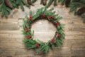 Christmas wreath made of spruce branches with holly berries on wooden board. Flat lay. Top view. Royalty Free Stock Photo