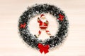 Christmas wreath with red bow on a beige wooden background and santa claus toy in center. Top view Royalty Free Stock Photo
