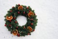 Christmas wreath with red spruce balls and dry citrus slices on a background of white snow Royalty Free Stock Photo