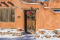 Christmas wreath on rustic door in snowy adobe wall, Santa Fe, NM Royalty Free Stock Photo